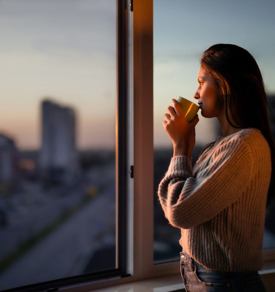 Profile view of beautiful woman drinking coffee by the window.